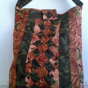 May include: A quilted tote bag with a brown, green, and pink floral pattern. The bag has a single strap and a button closure.
