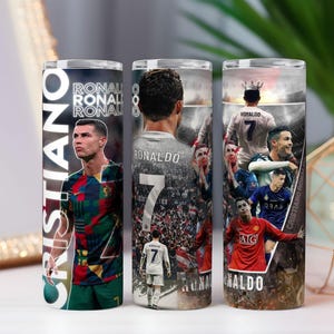 May include: Three stainless steel tumblers featuring images of Cristiano Ronaldo. The tumblers display various action shots and portraits of the soccer star, with the name "Cristiano" and "Ronaldo" prominently displayed. The tumblers are cylindrical and designed for beverages.