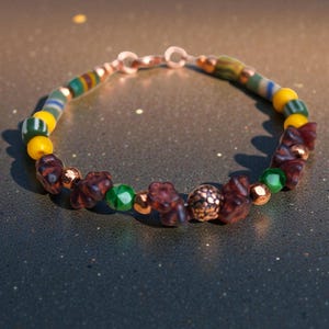May include: A handmade bracelet featuring a mix of colorful beads. The bracelet includes yellow, green, and brown beads, along with copper-colored accents. The clasp is also copper-colored. The bracelet is designed for everyday wear.