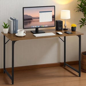 May include: A brown rectangular desk with black metal legs. The desk is set up with a computer monitor, keyboard, mouse, speaker, lamp, and a cup of coffee. A small plant and books are also on the desk.