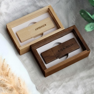 Könnte beinhalten: Zwei USB-Sticks aus Holz in passenden Holzkisten. Eine Kiste ist hellfarbig mit dem Namen "ANDERSON" auf dem USB-Stick graviert. Die andere Kiste ist dunkel gefärbt mit den Namen "RAJ & POOJA" graviert. Beide USB-Sticks sind rechteckig.