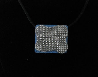 Silver pendant with blue base and geometric patterned medallion
