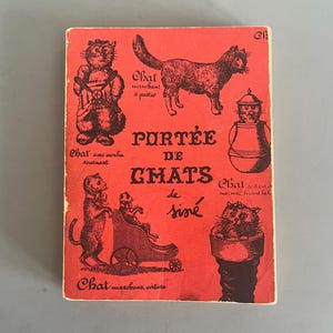 May include: A vintage red book cover with brown illustrations of cats in various poses. The French text "PORTÉE DE CHATS de siné" is prominently displayed. The cover has a worn appearance.