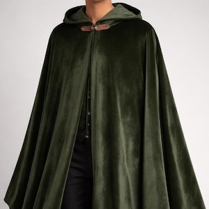 May include: A dark green velvet cloak with a hood. The cloak has a button closure and a leather clasp at the neck. The cloak is a flowing, full-length garment.