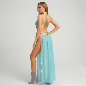 May include: A gold and blue costume with a high collar and a flowing skirt. The top is gold, with a blue bra underneath. The skirt is light blue with gold trim and a high slit. Gold arm cuffs and gray boots complete the look.