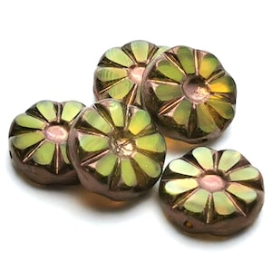 Könnte beinhalten: Fünf blütenförmige Perlen mit Metallic-Finish. Die Perlen haben eine dunkelbraune Grundfarbe mit grünen und goldenen Blütenblättern und einem rosa Zentrum. Ideal für die Schmuckherstellung.