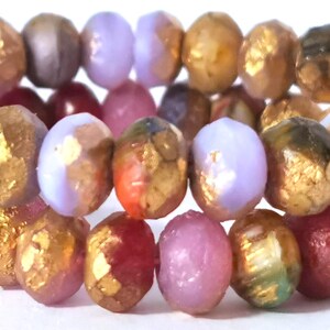 Könnte beinhalten: Nahaufnahme einer Sammlung farbenfroher Perlen. Die Perlen sind oval geformt und weisen eine Mischung aus Farben auf, darunter Gold, Lila, Rosa und Rot. Einige Perlen haben eine metallisch goldene Oberfläche.