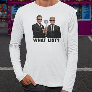 A person wearing a white long-sleeved shirt with a graphic design featuring two men in suits and sunglasses, holding a spoon, and the text "WHAT LIST?"