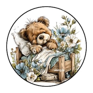 May include: A watercolor illustration of a teddy bear in a wooden bed, surrounded by blue and white flowers. The bear is nestled under a blanket and pillow. The word "sample" is visible on the bed.