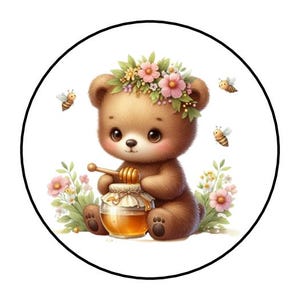 May include: A brown teddy bear illustration within a black circle. The bear wears a floral crown and holds a honey dipper over a jar of honey. Bees and flowers surround the bear, creating a whimsical, nature-themed design.