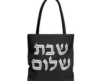 Könnte beinhalten: Schwarze Tragetasche mit weißem hebräischen Text. Die Tasche hat schwarze Griffe und einen schwarzen Körper. Der Text lautet "Schabbat Schalom" in einer stilisierten Schriftart. Die Tasche ist zum Tragen von Gegenständen bestimmt.
