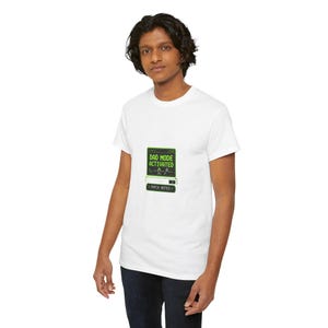 May include: A white short-sleeved t-shirt featuring a graphic of a computer screen with green text that reads DAD MODE ACTIVATED and a button below labeled PATCH NOTES. The design includes small icons of a baby bottle and a pacifier.