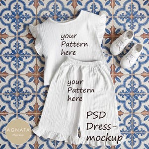 May include: White two-piece outfit with ruffled sleeves and hem, featuring the text "your Pattern here" and "PSD Dress-mockup". Includes a pair of white sneakers. The outfit is displayed on a patterned tile surface.