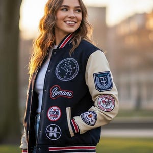 May include: A navy and cream varsity jacket with various patches. The jacket features red and white striped trim on the cuffs and waist. A white shirt is worn underneath.