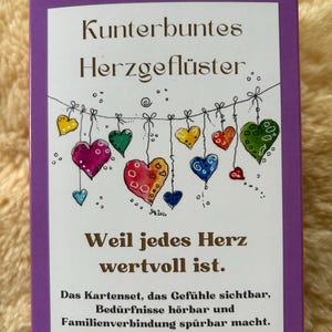 May include: A purple card featuring the German text "Kunterbuntes Herzgeflüster" and a string of illustrated hearts. The card also includes the text "Weil jedes Herz wertvoll ist."