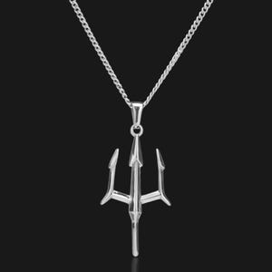 Puede incluir: Un collar con colgante plateado con un dise&ntilde;o de tridente. El tridente, una lanza de tres puntas, cuelga de una delicada cadena. El collar se muestra sobre un fondo oscuro, resaltando el metal brillante del colgante y la cadena.