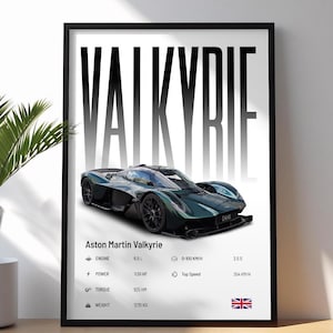 May include: Framed print featuring an Aston Martin Valkyrie. The image showcases a dark green sports car with detailed specifications, including engine size, horsepower, torque, and weight. The text "VALKYRIE" is prominently displayed at the top.