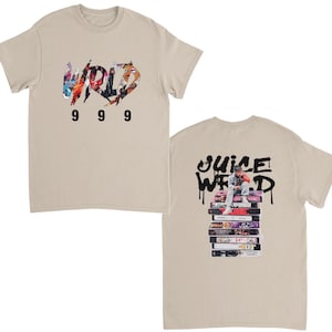 以下が含まれることがあります： グラフィックデザインのベージュTシャツ。Tシャツの前面には、カラフルなデザインで「WRD」の文字と、その下に数字の「9 9 9」が描かれています。Tシャツの背面には、「JUICE WRLD」の文字と、カセットテープの山に座っている人のグラフィックが描かれています。