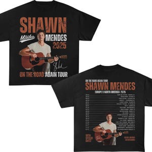 Könnte beinhalten: Schwarzes T-Shirt mit einer Grafik von Shawn Mendes mit Gitarre, dem Text "SHAWN MENDES 2025" und "ON THE ROAD AGAIN TOUR". Auf der Rückseite des Shirts sind Tourdaten für Europa und Nordamerika aufgeführt.
