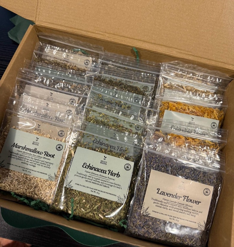 Puede incluir: Una caja de cart&oacute;n que contiene varias bolsas de pl&aacute;stico transparente llenas de hierbas y flores secas. Las etiquetas incluyen Marshmallow Root, Echinacea Herb y Lavender Flower, con un peso neto de 15g cada una.