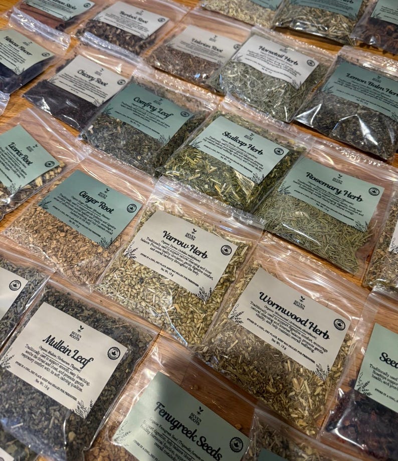 Puede incluir: Una colecci&oacute;n de bolsas de pl&aacute;stico transparente llenas de diversas hierbas y ra&iacute;ces secas, cada una con una etiqueta verde claro con el logotipo de Seven Roots, el nombre del producto y el peso neto en gramos. El surtido incluye Mullein Leaf, Yarrow Herb y Wormwood Herb.