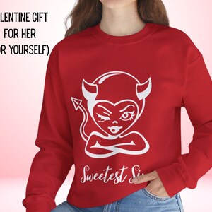 Könnte beinhalten: Ein rotes Sweatshirt mit einer weißen Grafik eines zwinkernden Teufels und dem Text "Sweetest Sin" darunter. Der Text "VALENTINE GIFT FOR HER (OR YOURSELF)" steht oben. Ein Valentinstagsgeschenk.