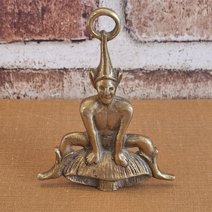 Könnte beinhalten: Messingfigur eines sitzenden Elfen mit spitzem Hut und Ring oben. Der Elf sitzt auf einem pilzförmigen Sockel. Die Figur hat einen Vintage-Look.