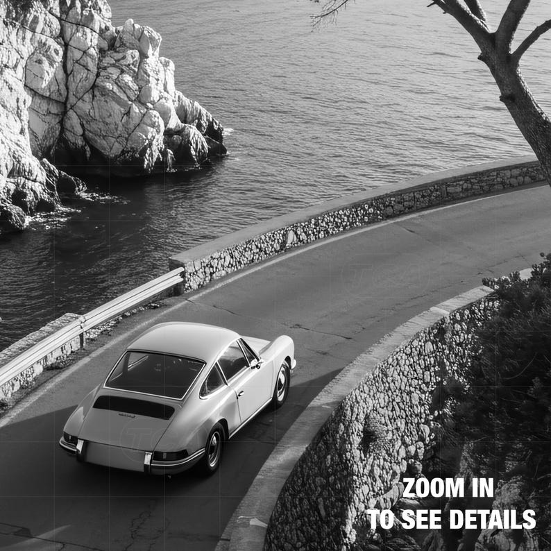 A vintage white sports car is driving on a winding coastal road, with a rocky cliff and the ocean in the background.