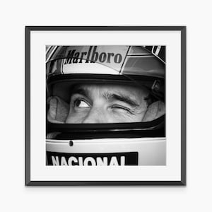 Puede incluir: Impresión enmarcada en blanco y negro de un piloto de carreras con casco. El casco tiene el logotipo de Marlboro y la palabra NACIONAL. El piloto está guiñando un ojo.