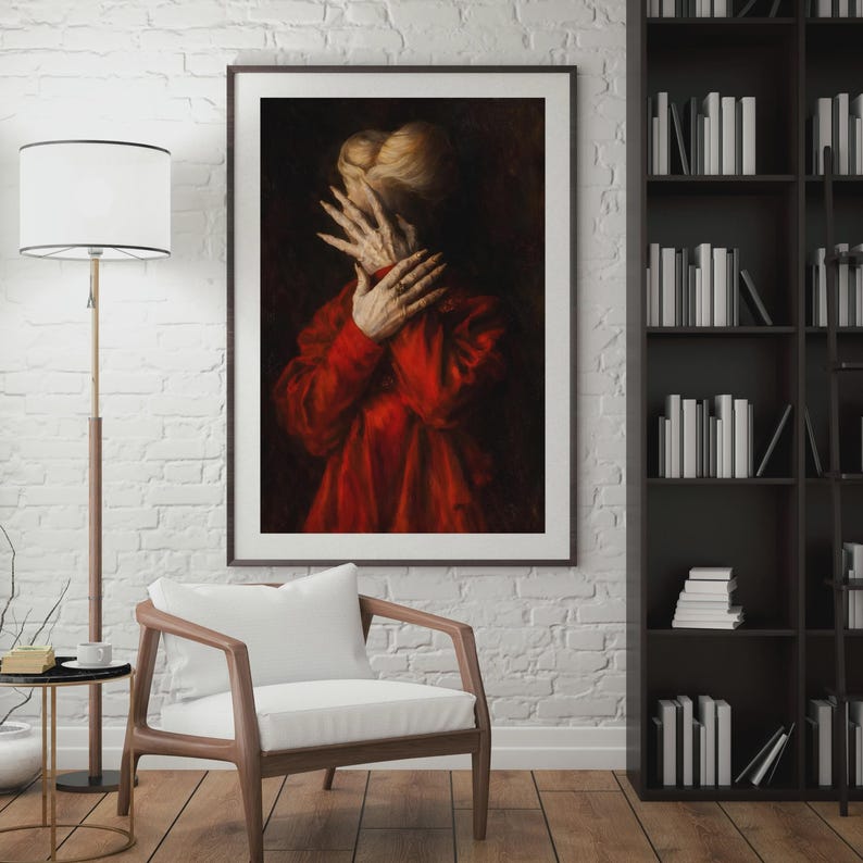 May include: A framed artwork depicts a person in a red garment, hands covering the face. The painting has a dark, dramatic aesthetic, with a focus on texture and shadow. The artwork is displayed in a living room setting.