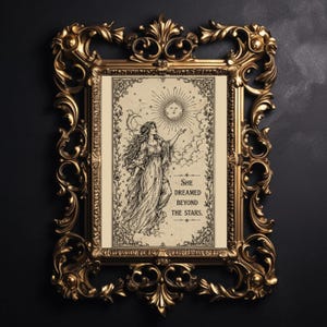 May include: An ornate gold-coloured framed art print. The print features a woman in a flowing gown reaching towards a sun and moon design. The text "She dreamed beyond the stars" is below the illustration. The frame has detailed scrollwork.