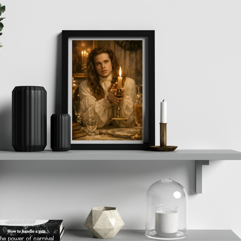 May include: A framed print featuring a person holding a lit candle, set on a table with glassware and a plate. The print is in a black frame, and the scene is lit by candlelight. Decorative black vases and a candle holder are on a shelf.