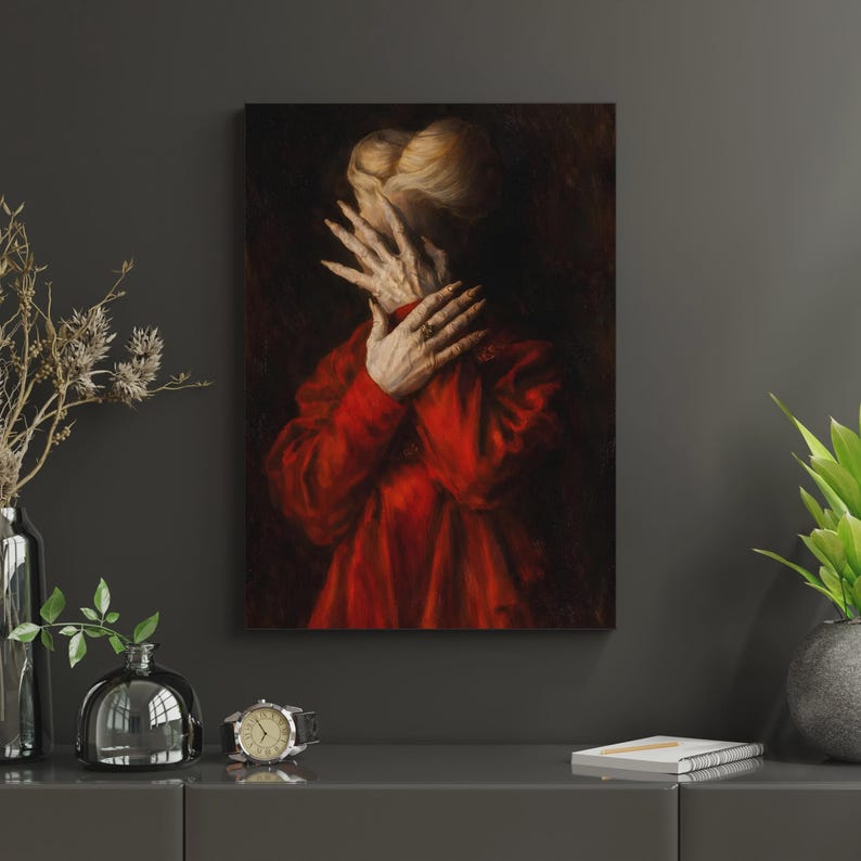 May include: An oil painting depicts a person in a red garment, hands covering the face. The artwork has a dark, dramatic background, with the subject's hands and face in focus. The painting is displayed on a dark gray wall.