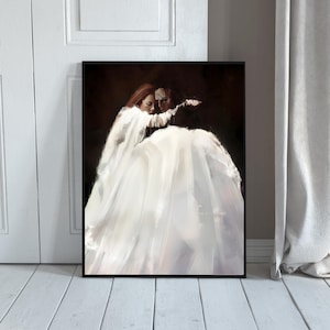 May include: A framed art print featuring an artistic depiction of two figures embracing. The figures are rendered in soft, blended brushstrokes, with a focus on a flowing white dress and a dark, contrasting background. The artwork evokes a sense of intimacy.
