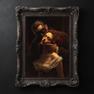 May include: An antique-style framed painting depicts a man in a mask embracing a woman. The woman wears a white dress and has a red rose in her hair. The ornate frame is dark gray.