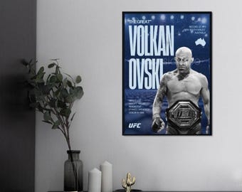 May include: A framed poster featuring Volkanovski, a UFC fighter, with the text "THE GREAT" and "VOLKAN OVSKI" in white. The poster has a blue background and includes the UFC logo. The fighter is wearing a championship belt.
