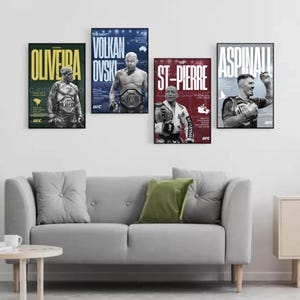 May include: Four framed UFC posters featuring fighters Oliveira, Volkanovski, St-Pierre, and Aspinall. Each poster has a black frame and displays the fighter's name in large letters, along with the UFC logo. The posters are hung above a gray sofa with a green pillow.