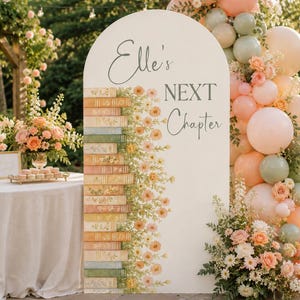May include: A white arched sign with the text "Elle's NEXT Chapter" and a floral and book design. The sign is decorated with peach and green balloons and flowers, creating a celebratory atmosphere.