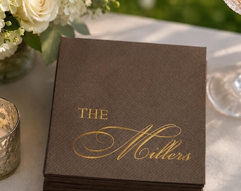 Könnte beinhalten: Ein Stapel quadratischer, dunkelbrauner Papierservietten mit dem goldfoliengeprägten Text "THE Millers" in einer Kombination aus Block- und Schreibschrift. Die Servietten haben eine strukturierte Oberfläche und sind ordentlich gestapelt.