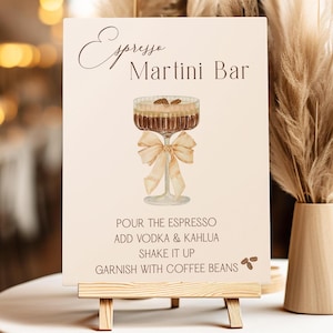 May include: A sign for an Espresso Martini Bar with a watercolour illustration of a martini glass with a brown ribbon and coffee beans. The sign reads "Espresso Martini Bar" and includes instructions for making the drink: "Pour the espresso, add vodka & Kahlua, shake it up, garnish with coffee beans."