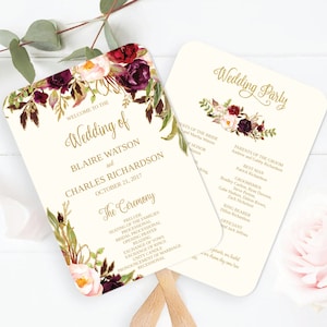 Puede incluir: Un abanico de programa de boda con un diseño floral en tonos burdeos, rosa y dorado. El texto dice "Bienvenido a la boda de Blair Watson y Charles Richardson, 21 de octubre de 2017". La parte posterior del abanico enumera la fiesta de bodas.