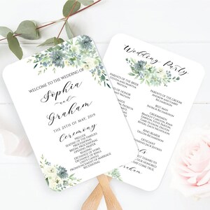 Può includere: Un ventaglio di programma per la cerimonia di matrimonio con un design ad acquerello di fiori bianchi e foglie verdi. Il testo sul ventaglio recita "Benvenuti al matrimonio di Sophia e Graham, il 25 maggio 2019, Cerimonia" e elenca l'ordine degli eventi della cerimonia. Il retro del ventaglio elenca la festa di matrimonio e i loro nomi.