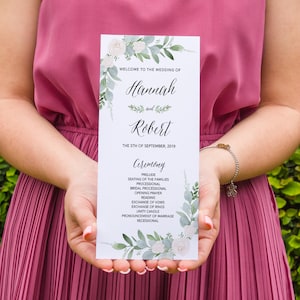 May include: A wedding ceremony program with a floral design featuring white flowers and green leaves. The program lists the order of events for the wedding of Hannah and Robert on September 5th, 2019.
