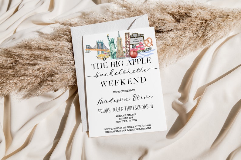 May include: A white invitation card with a watercolor illustration of New York City landmarks, including the Statue of Liberty, the Brooklyn Bridge, and a yellow taxi cab. The text on the card reads "The Big Apple Bachelorette Weekend" and includes the name "Madison Olive" and the date "Friday, July 8 thru Sunday, 11".
