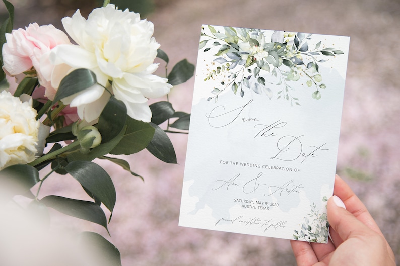May include: Save the Date card with a watercolor floral design in shades of green and gold. The card features the text "Save the Date" in a script font and the names "An & Aiste" with the date "Saturday, May 9, 2020" and location "Austin, Texas".