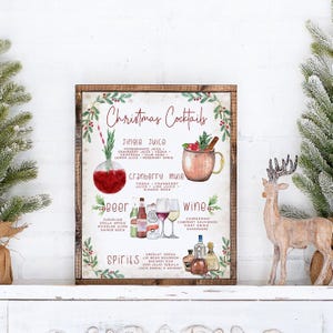 May include: A framed sign titled Christmas Cocktails featuring watercolor illustrations of drinks including Jingle Juice, a Cranberry Mule, beer, wine, and spirits with ingredient lists and brand names printed in red and black text on a white background.