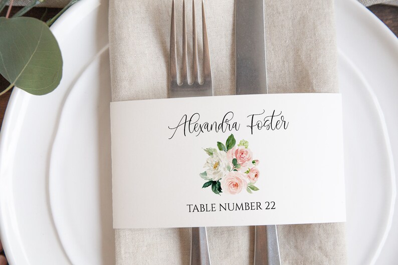 May include: A white place card with a floral design and the text "Alexandra Foster" and "Table Number 22".