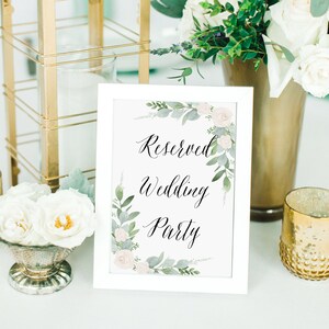 K&ouml;nnte beinhalten: Ein wei&szlig; gerahmtes Schild mit einem floralen Design und dem Text "Reserved Wedding Party" in schwarzer Kalligraphie.