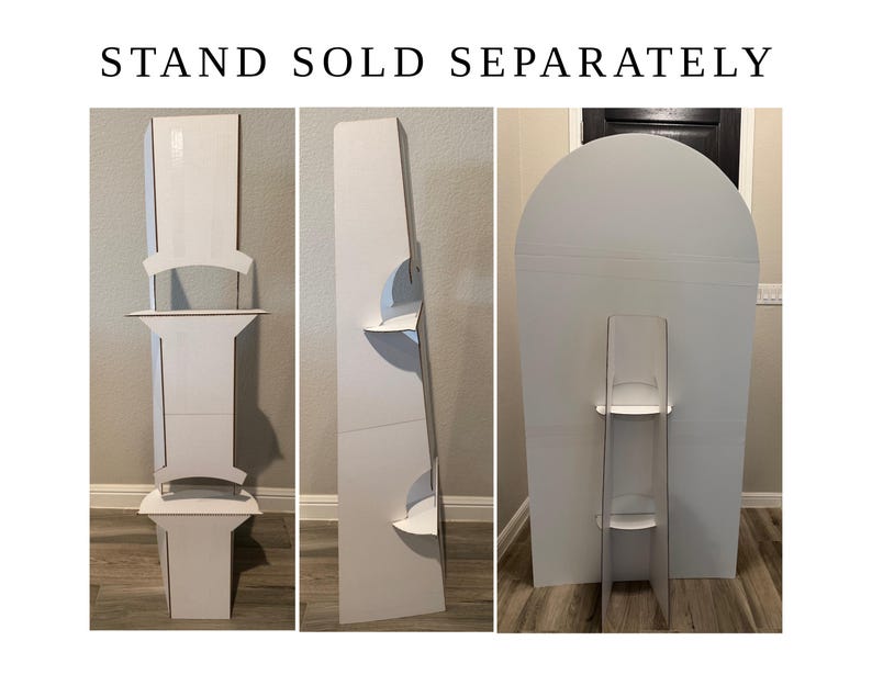 May include: A white cardboard display stand with multiple shelves, shown from three different angles. The text STAND SOLD SEPARATELY is printed at the top. The structure features a tall vertical back panel and several horizontal shelves.