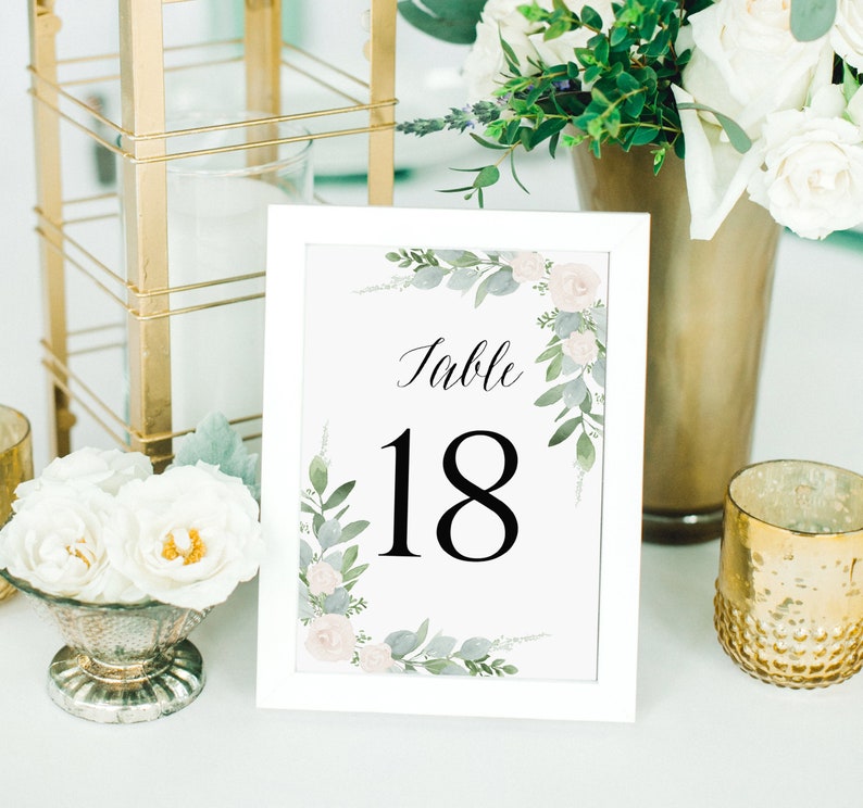 K&ouml;nnte beinhalten: Wei&szlig;e, gerahmte Tischnummernkarte mit floralem Design und dem Text "Tisch 18" in Schwarz.